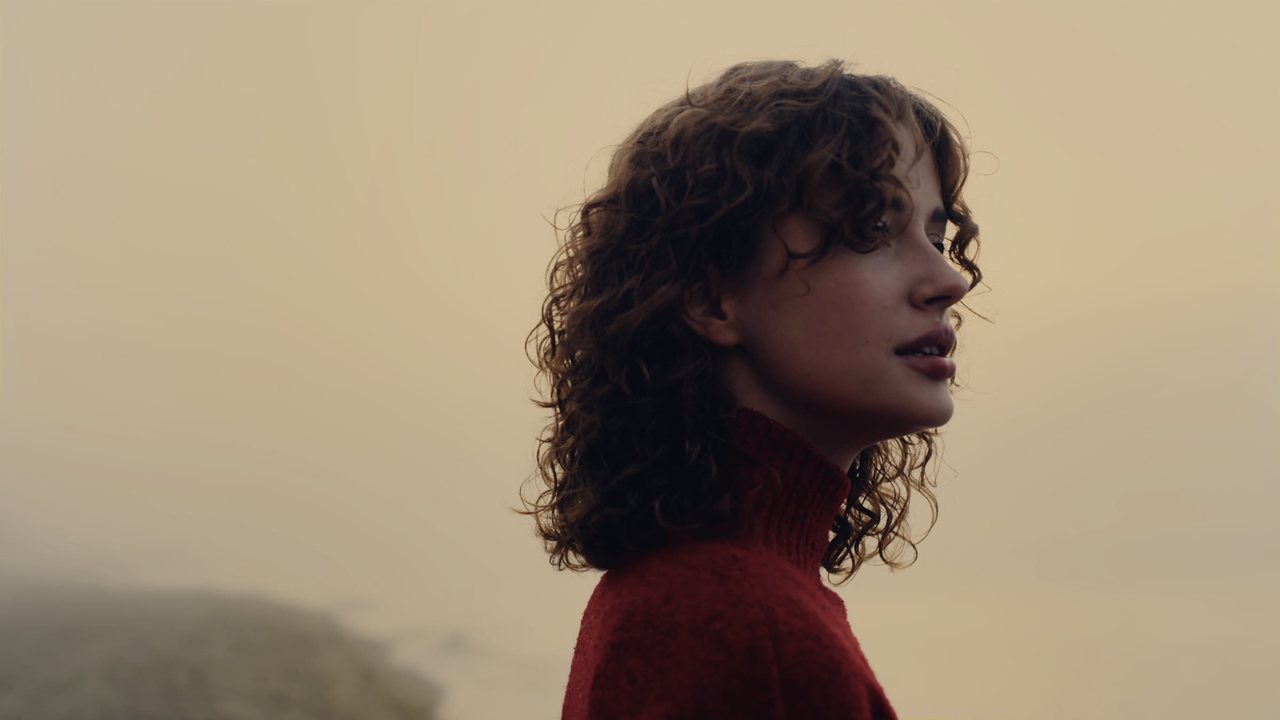 A woman in a red sweater on a misty coast